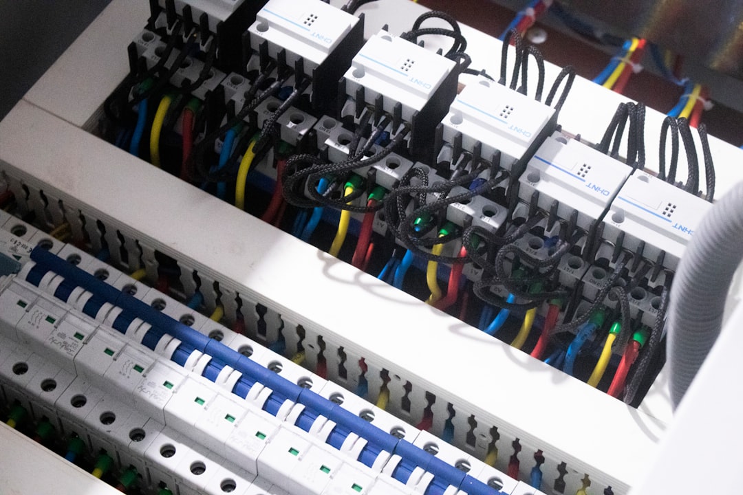 Electrician actively working on open electrical panel with visible circuit breakers and professional workspace